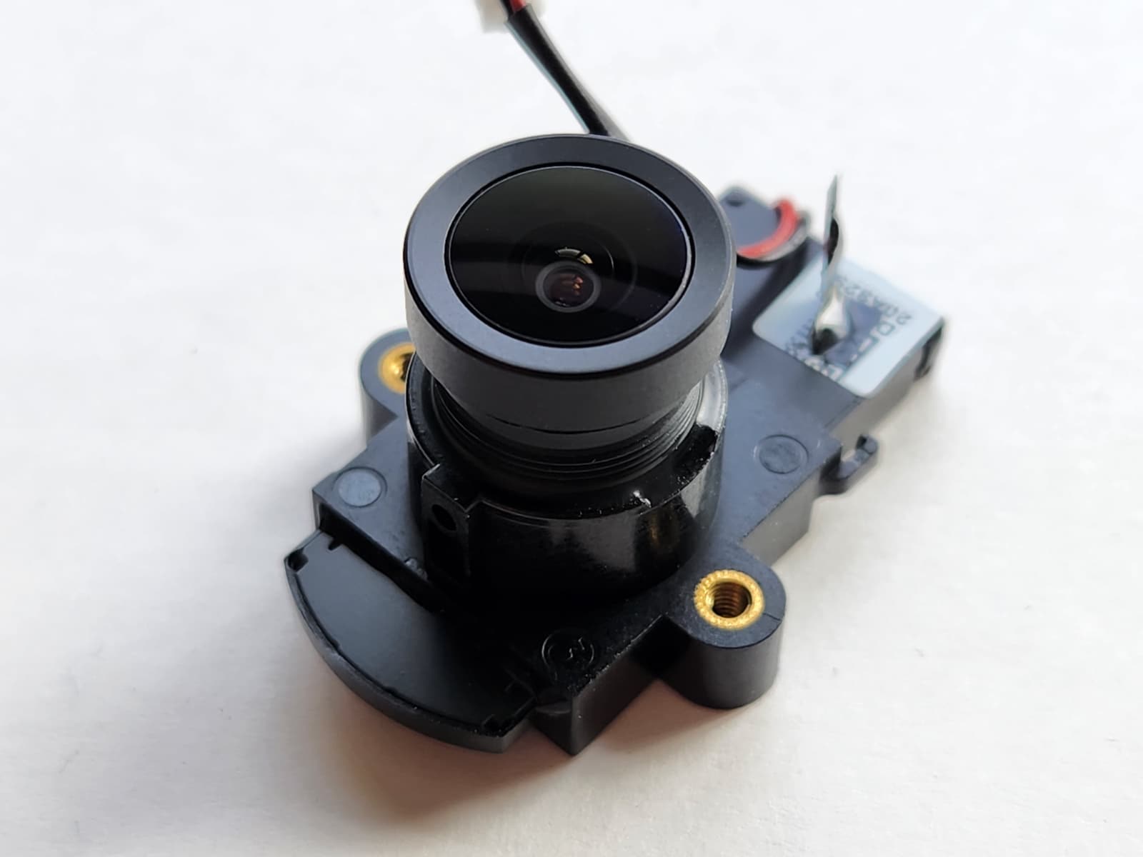 A matte black camera lens, about the size of the end of a pinky finger